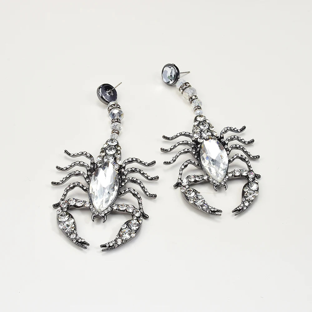 Scorpion-shaped earrings with crystal details on a light gray background Scorpion-shaped earrings with crystal details on a light gray background
