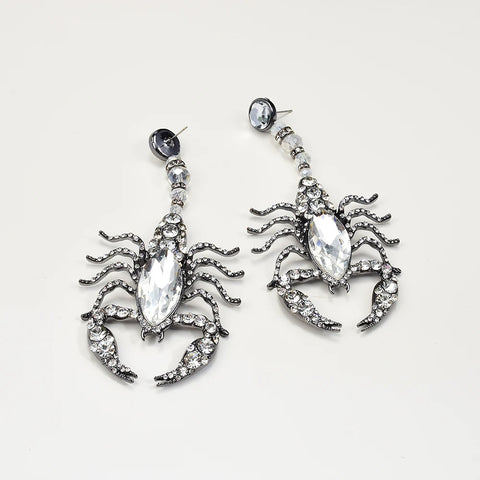 Scorpion-shaped earrings with crystal details on a light gray background Scorpion-shaped earrings with crystal details on a light gray background
