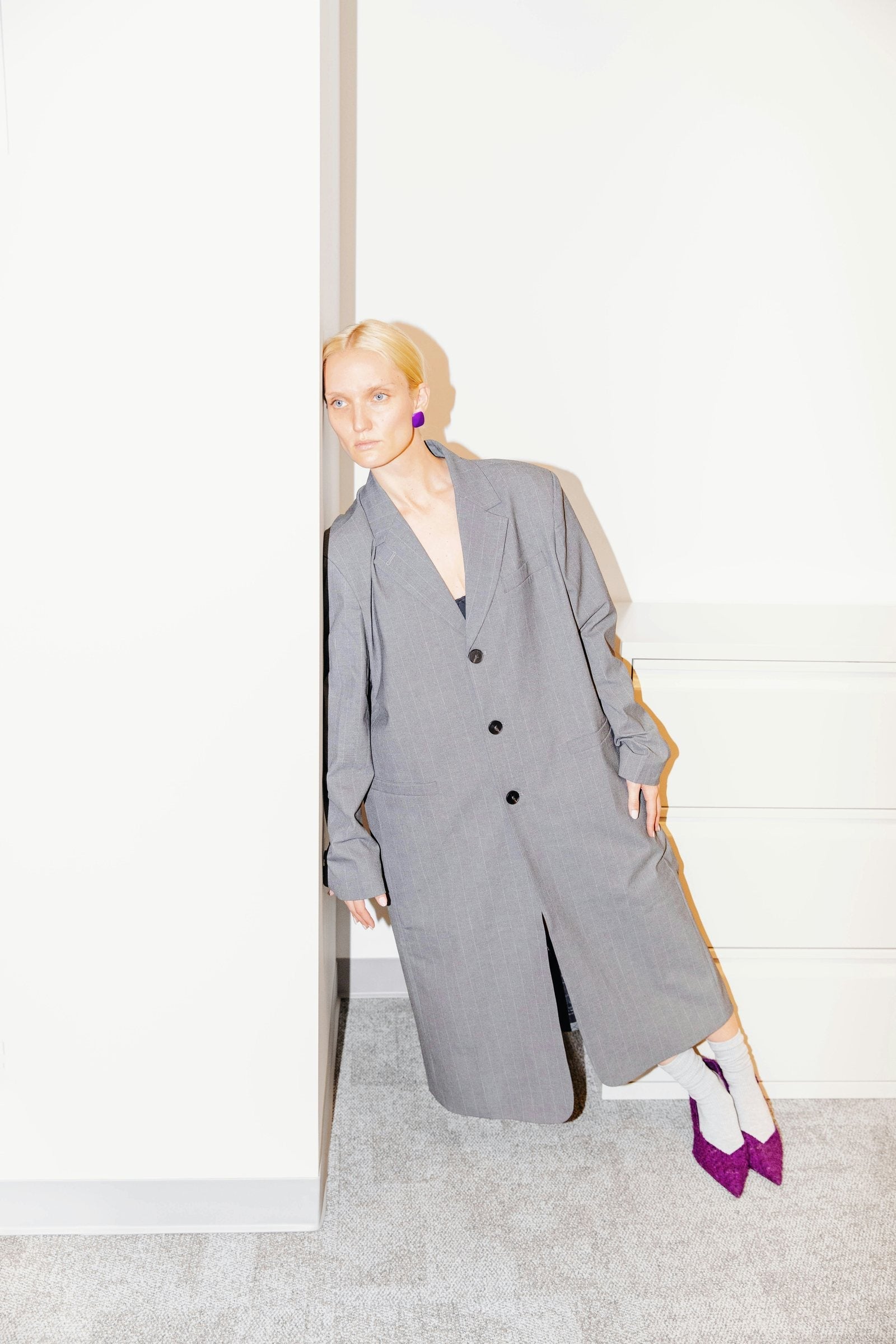 Editorial: oversized grey pinstripe coat with purple statement earrings and purple heels