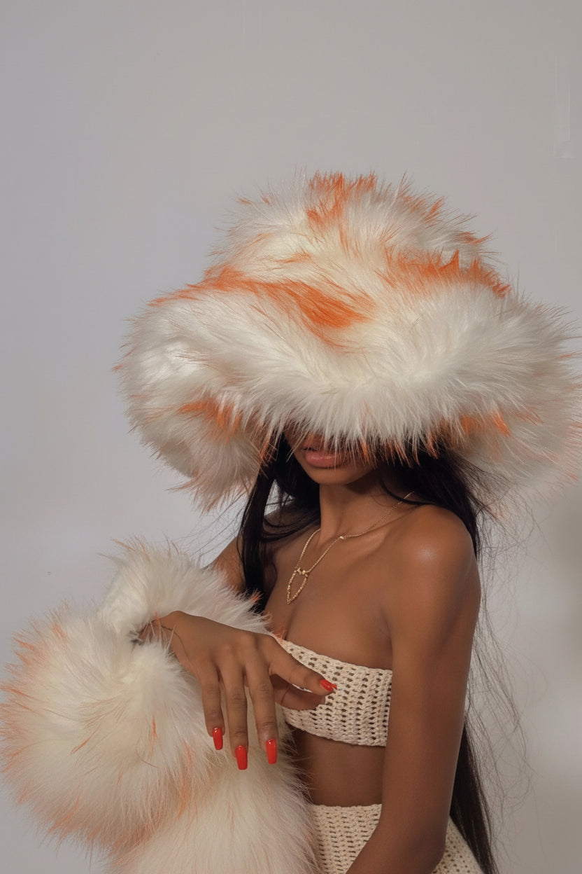 Person wearing a large white and orange feathered hat against a plain background Main image