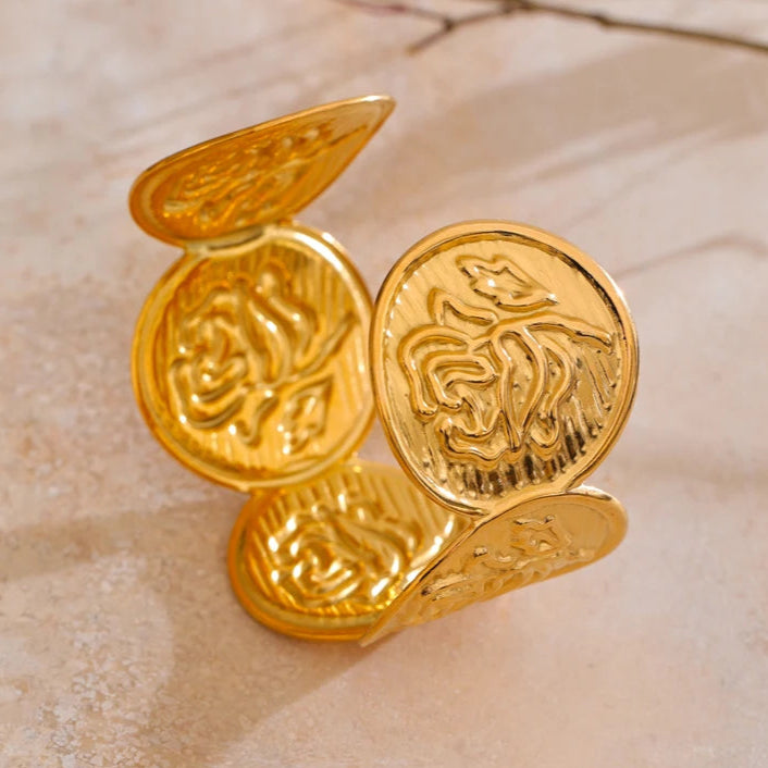 Gold coin-shaped earrings on a marble surface