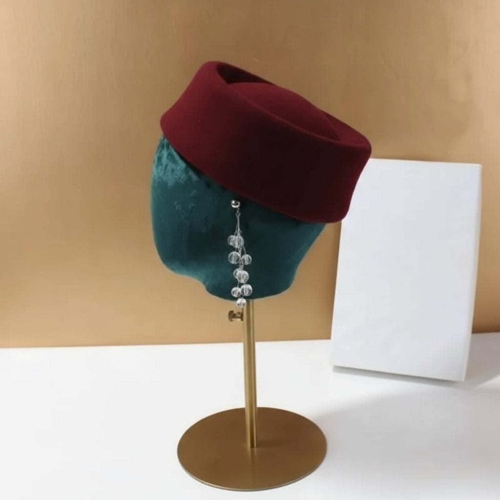 Red beret on a mannequin head with a gold stand against a beige background